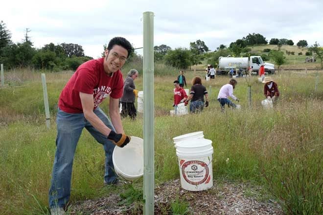 Magic volunteers work a bucket brigade from a tank truck into the field to water young trees. Photo: courtesy of Magi