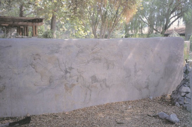 A straw bale wall provides spatial definition, a handsome backdrop for plants and creativity in the application of simulated petroglyphs on its finished surface. (The Arboretum of Los Angeles County)