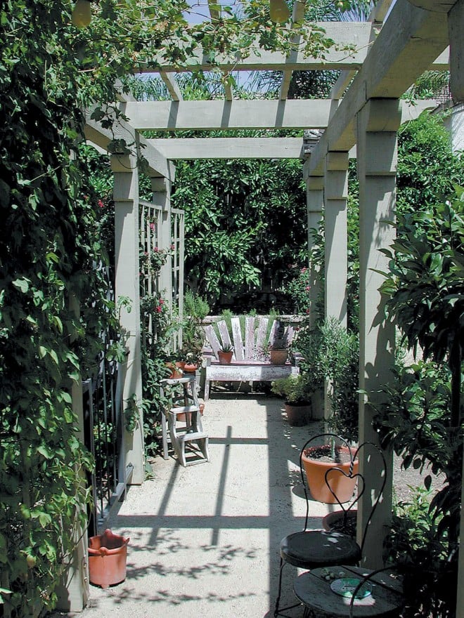 Terracotta pots and garden furniture take advantage of the shade produced by the arbor