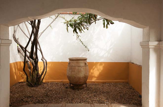 Shadow and light animate a living tableau featuring a large clay vessel off the porte-cochere. Photo: Jeff Dunas.