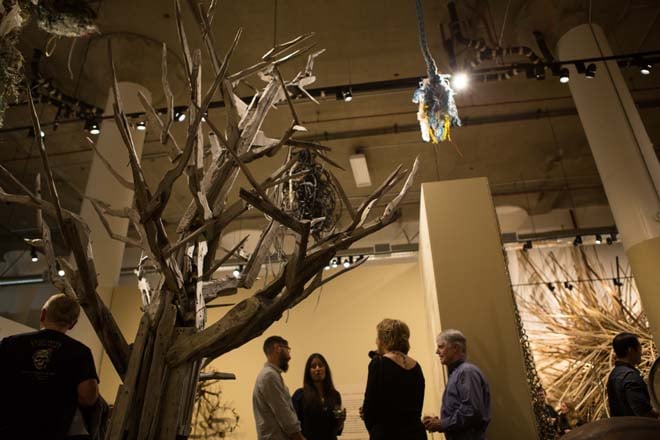 Museum visitors mingle beneath the canopy of a tree created from recycled and found materials at the opening of “A Visual Transparency Project,” June 28, 2014. Photo: Luke Judd